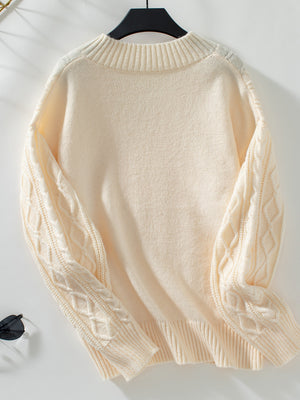 Cream cable knit sweater with diamond pattern sleeves and keyhole neck detail.
