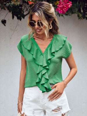 Green V-neck blouse with ruffled front and flutter sleeves, styled with white shorts.