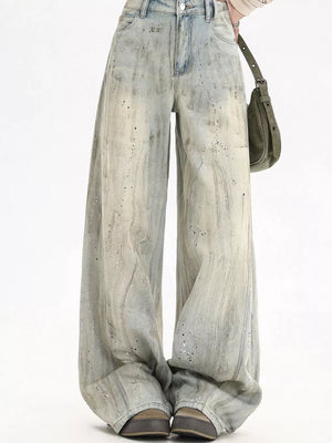Light vintage wash wide-leg denim jeans with distressed paint splatter details.