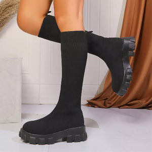 Black sock knee-high boots with chunky platform sole and ribbed cuff.