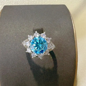 Sterling silver ring with a bright blue center stone surrounded by clear accent stones.