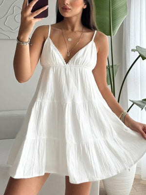 White cotton tiered mini dress with lace trim and spaghetti straps.
