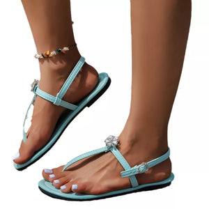 Lake blue flat sandals with floral gem embellishments and ankle straps.