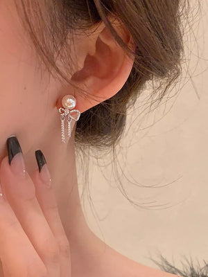 Luminous pearl drop earrings with bowknot and crystal fringe detail.
