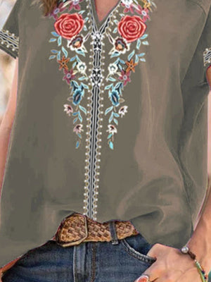Army green blouse with floral embroidery and notched neckline, styled with jeans and a belt.