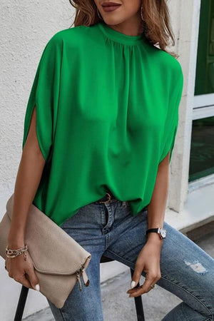 Green drape sleeve blouse with mock neck and split sleeves, styled with jeans.