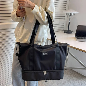 Black dual-compartment travel tote with metallic trim and dual zippers.