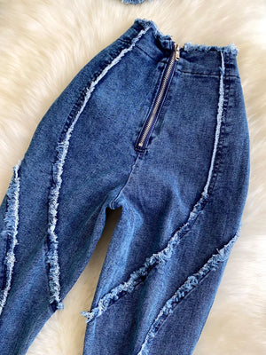 Denim flare pants with raw hem detailing and a silver zipper closure.