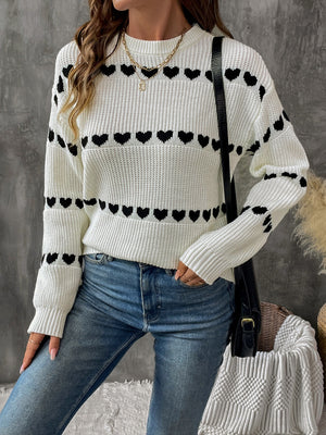 Cream knit sweater with black heart pattern, long sleeves, crew neck, casual style.