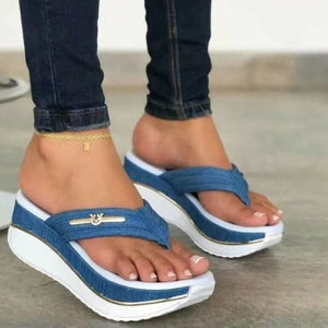 Blue denim platform flip-flops with elegant emblem detail and white sole.