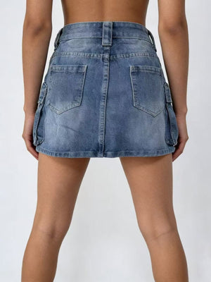 Plus size washed denim cargo skirt in dark blue with button closure and utility pockets.