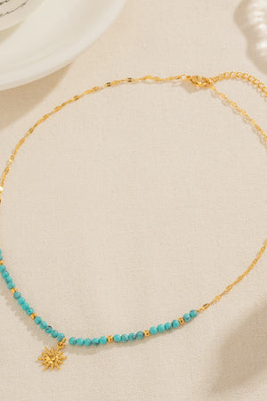 Gold celestial sunburst beaded necklace with turquoise beads and gold accents.