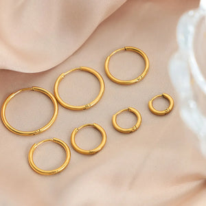 Gold vermeil huggie earrings in multiple sizes on a satin background.