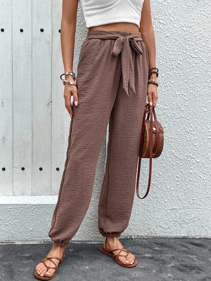 Brown textured tie-waist jogger trousers with elastic cuffs.