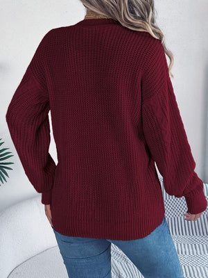 Burgundy cable knit cardigan with balloon sleeves and buttoned front.
