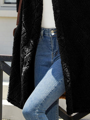Black quilted teddy bear coat with buttons and patch pockets, worn with jeans.