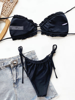 Black ruffle tie bikini set with string bikini bottoms and denim shorts.