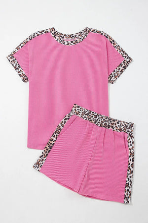 Pink ribbed pajama set with crew neck top and shorts, featuring leopard trim detail.