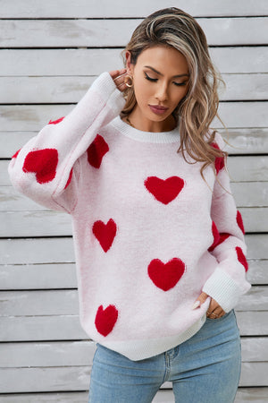 White crewneck sweater with allover red heart appliqué and ribbed cuffs.