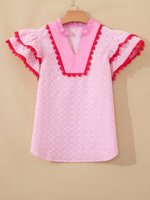 Pink eyelet embroidered blouse with flutter sleeves and red lace trim.