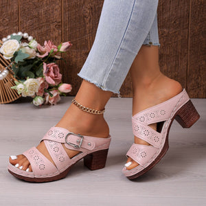Pink laser-cut criss-cross block heel sandals with buckle detail and open toe.