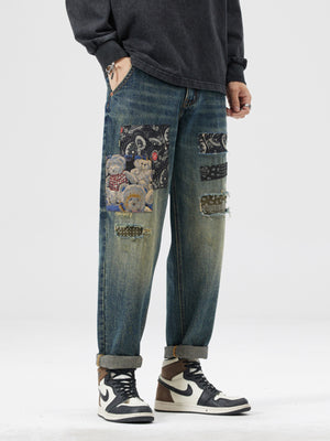 Men's distressed blue jeans with patchwork featuring teddy bears and paisley pattern.