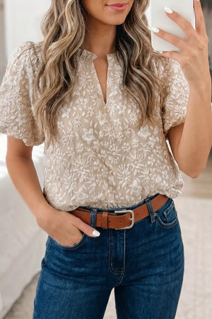 Charming floral jacquard shirt with puff sleeves and V-neck, styled with blue jeans.