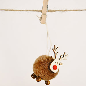 Whimsical pom-pom reindeer ornament with wooden antlers and red nose, hanging from twine.