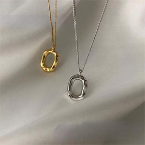 Geometric pendant necklaces in gold and silver with organic oval shapes on delicate chains.