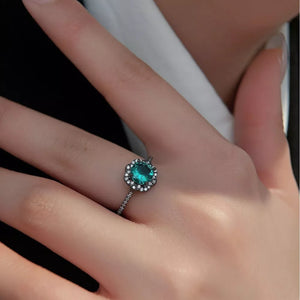 Elegant sterling silver ring with a teal zircon center and halo of small clear stones.