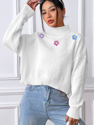 White cropped turtleneck sweater with embroidered floral details and ribbed trim.