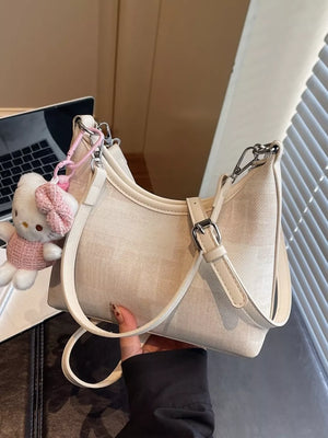 Ivory pu leather crescent shoulder bag with buckle detail and Hello Kitty charm.