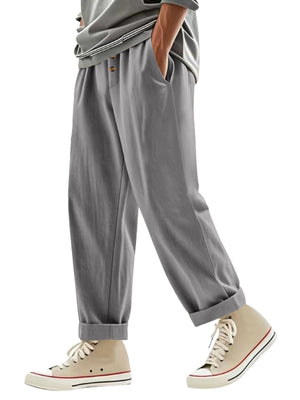 Men's grey loose fit sweatpants with drawstring waist and button detail.