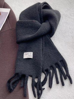 Plush fringe scarf in solid black with a cozy texture and fringed ends.