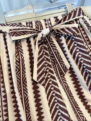 Maternity wide-leg pants in brown and white geometric print with a tie bow detail.