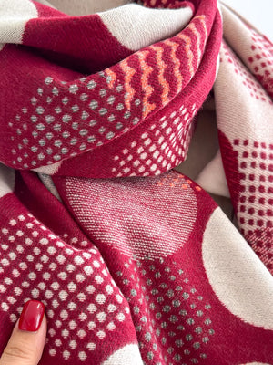 Deep red and cream textured scarf with polka dot and chevron patterns.