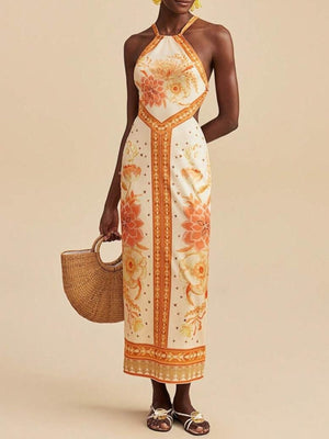 Backless maxi dress with orange floral print, halter neck, and side cutouts.