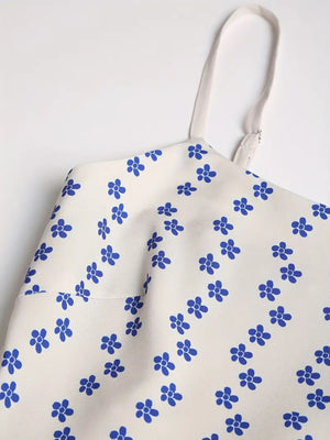Spaghetti strap midi dress in cream with blue floral print and adjustable straps.