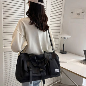 Black utility traveler holdall duffel bag with buckle details and multiple pockets.