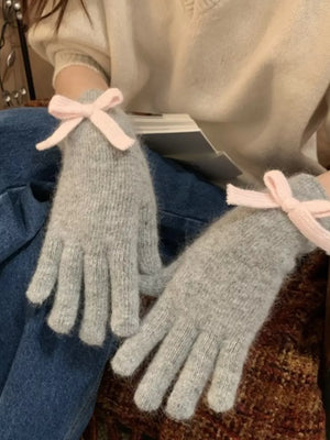 Light gray knit gloves with pink bows, cozy women's winter accessories.