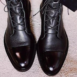 Black leather ankle boots with glossy cap toe and lace-up front