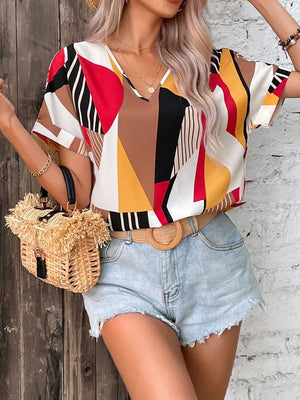 Geometric print V-neck blouse with short sleeves and a multicolor abstract pattern.