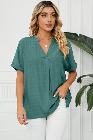 Dark green blouse with rolled sleeves and v-neckline, featuring a subtle textured pattern.