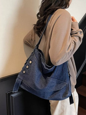 Relaxed denim crossbody bag with button accents and adjustable strap.