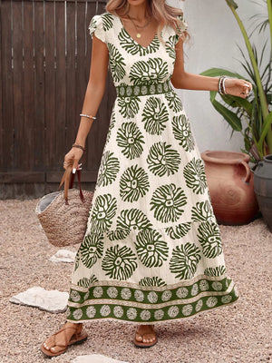 Botanical print V-neck maxi dress in cream with green botanical pattern, cap sleeves, and tiered skirt.