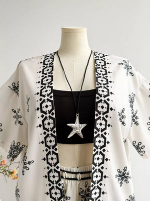 White polyester kimono jacket with black geometric and floral print, worn over a black crop top and shorts.