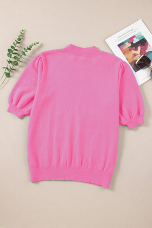 Pink knit top with mock neck and puff sleeves.