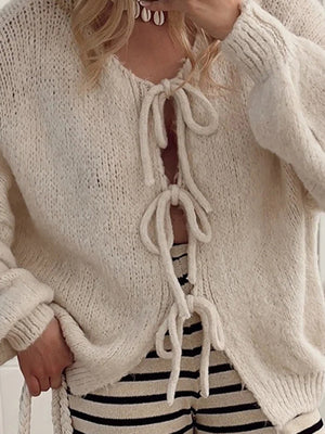 Beige knit cardigan with balloon sleeves and lace-up front detail.