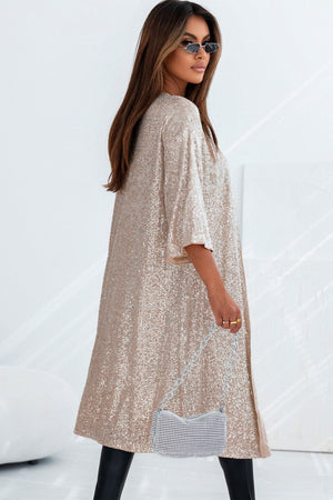 Beige sequin kimono jacket with wide sleeves and open front, styled with a rhinestone handbag.