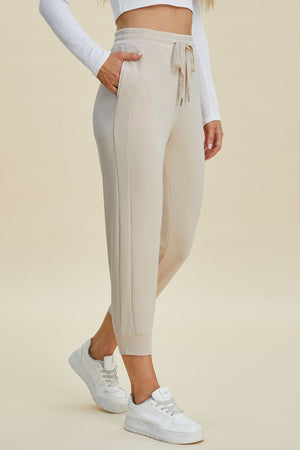 Beige joggers with drawstring waist and side seam detail.